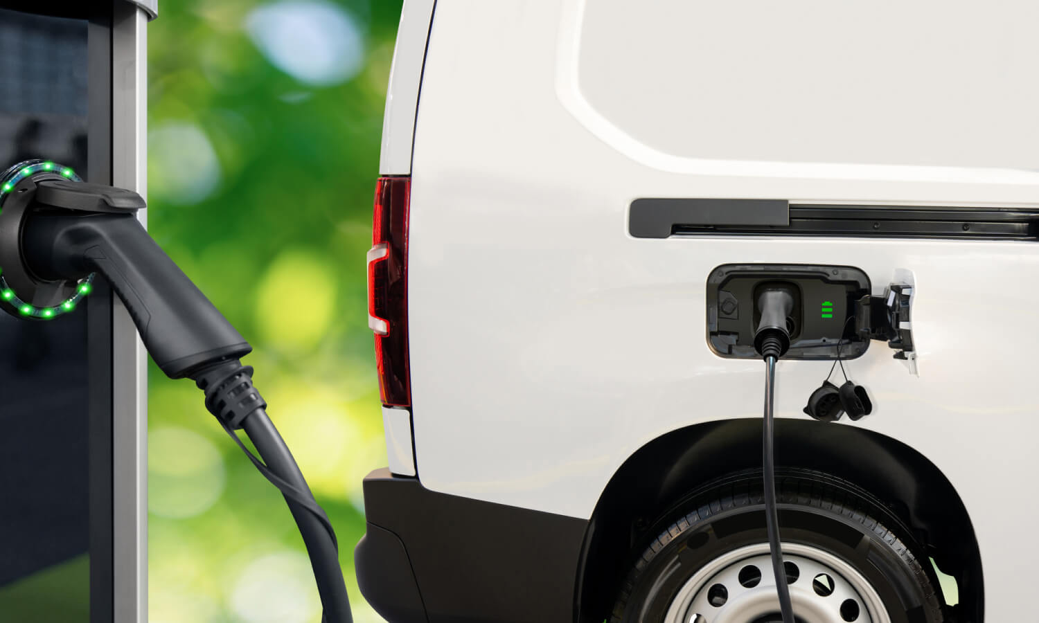 Electric van charging at a station, with a green blurred background.