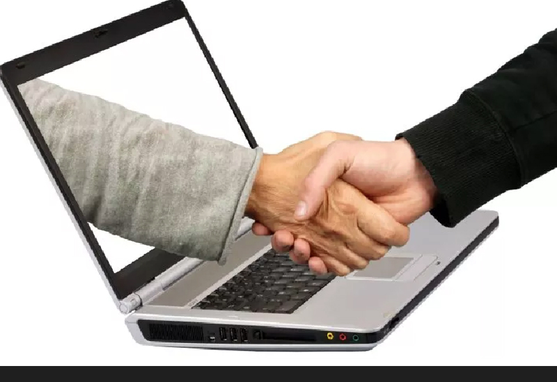 A handshake extending from a laptop screen, symbolizing virtual agreement or online communication.