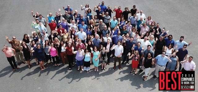 A large group of people smiling and waving at the camera; text reads "Best Companies to Work for in Business 2018.