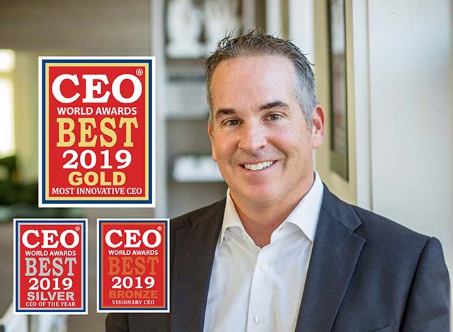 Smiling man in a suit next to three CEO World Awards plaques from 2019: Gold, Silver, and Bronze.