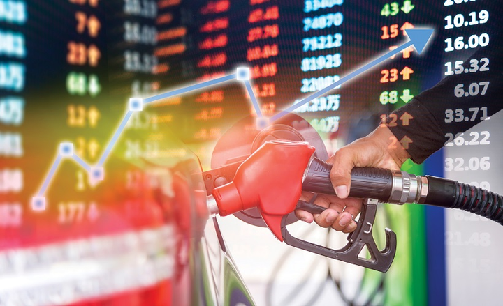 A fuel pump nozzle with financial data and a rising graph in the background.