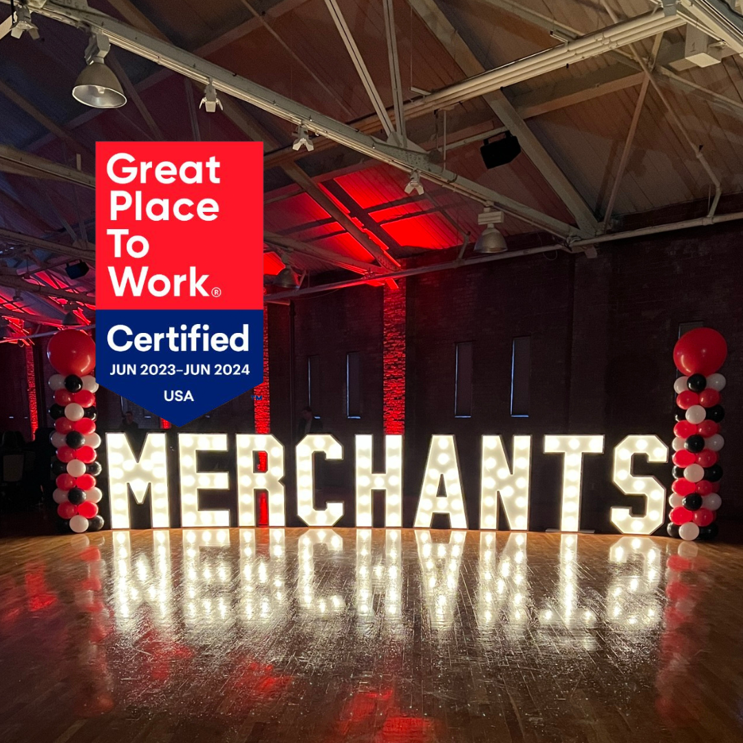 Illuminated "MERCHANTS" sign with a "Great Place To Work" certification banner, red and white balloons.
