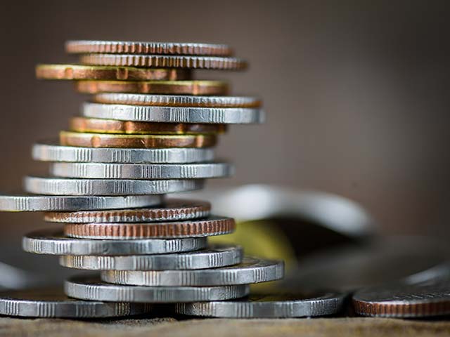 Close-up of stacked coins with varied colors and textures against a blurred background.