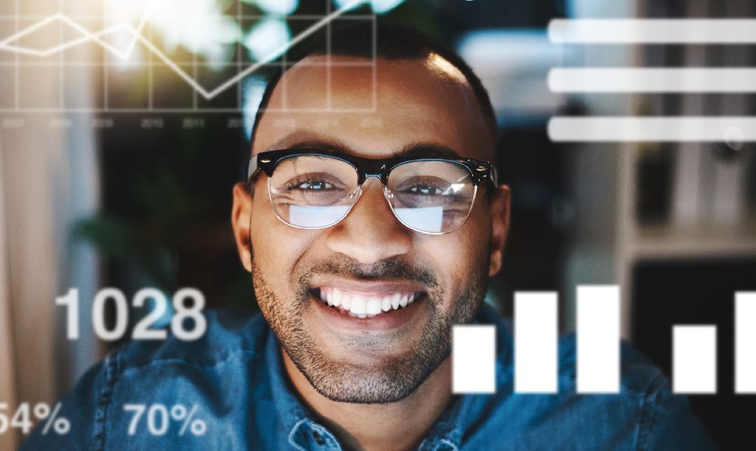 Man with glasses smiling, surrounded by digital graphs and charts overlaying the image.