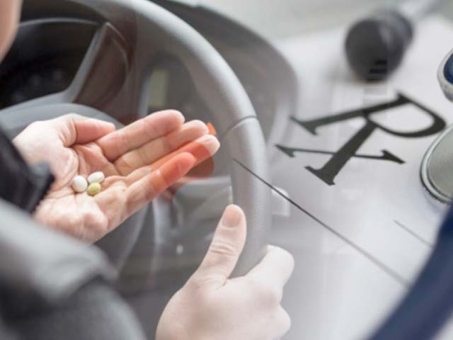 Person holding pills while driving, with a prescription symbol overlay indicating a focus on meds and driving safety.