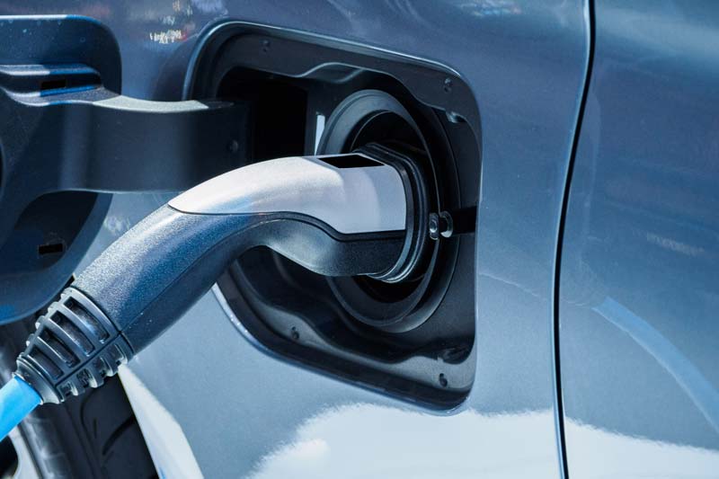 Close-up of an electric vehicle charging plug connected to a car's charging port.