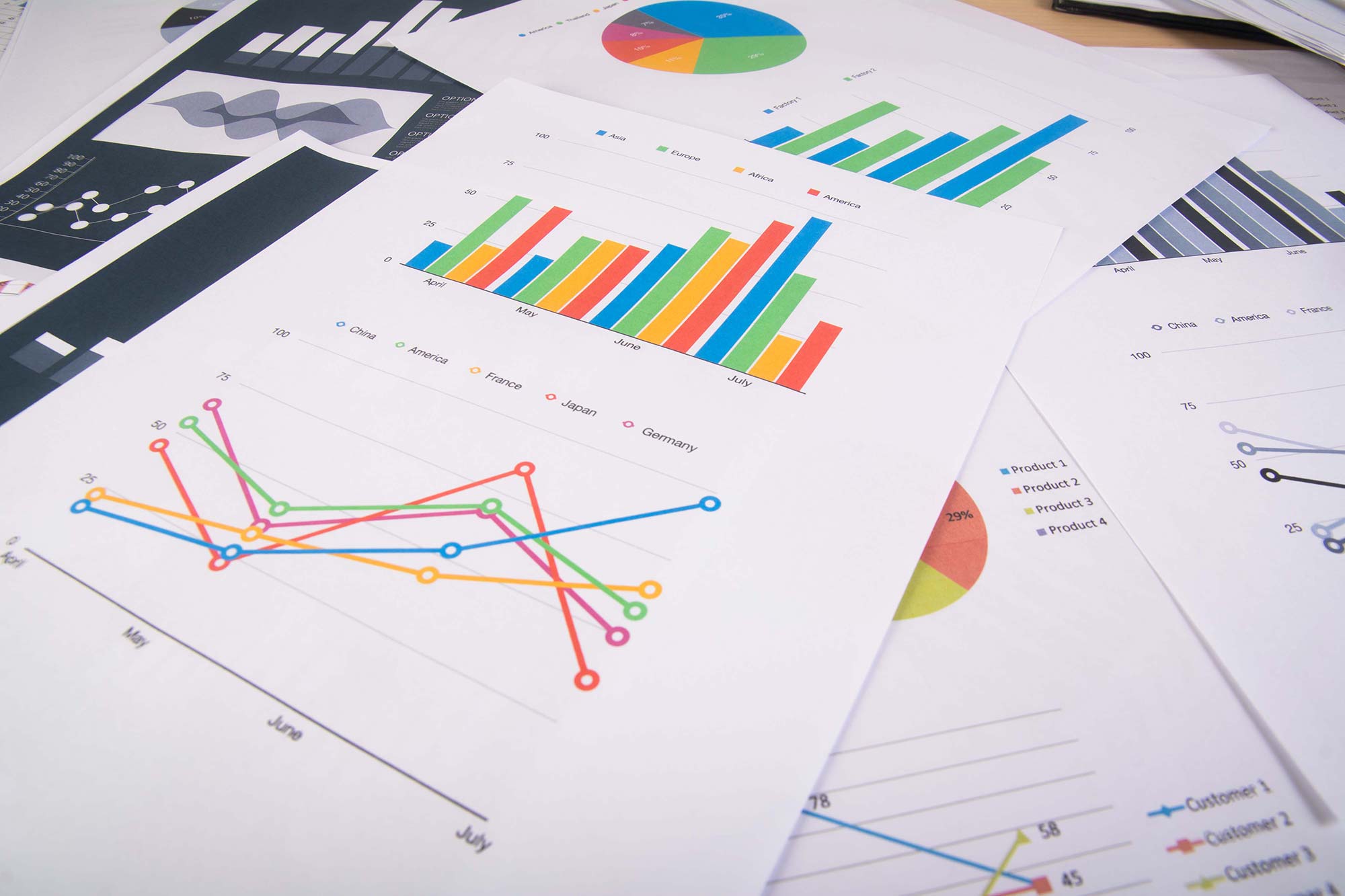Various charts and graphs on sheets of paper, displaying colorful bar and line graphs with data comparisons.