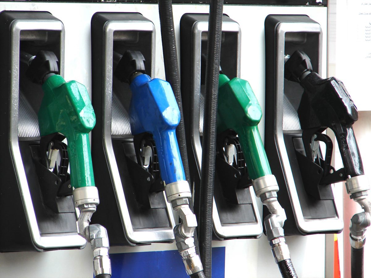 Close-up of four fuel nozzles at a gas station, with green and blue handles.