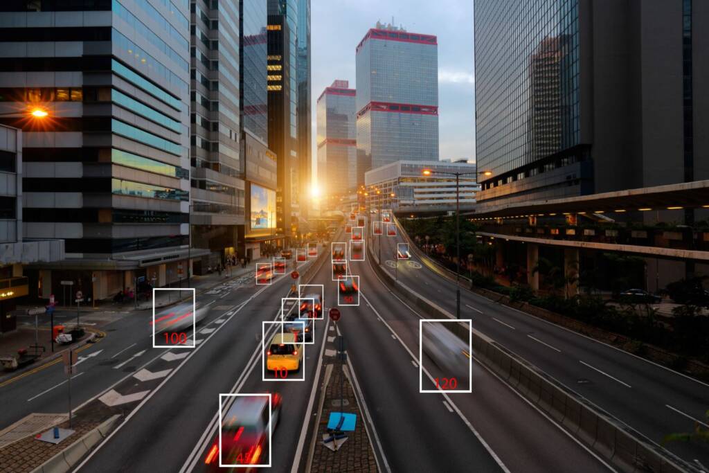 A bustling city highway at sunset with moving vehicles highlighted by sensor boxes.