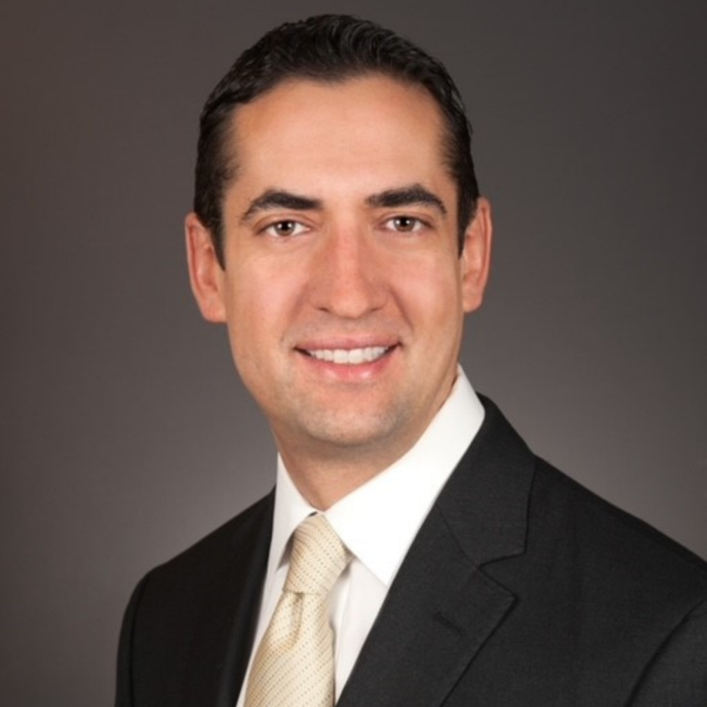 Smiling man in a suit and tie against a dark background.