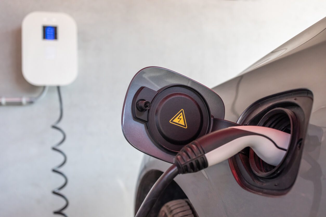 Electric vehicle plugged into a wall-mounted charging station.