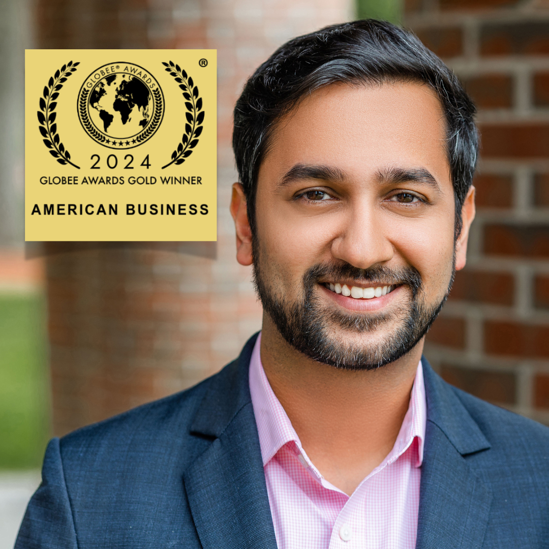 Smiling man in suit beside 2024 Globee Awards Gold Winner logo on a brick background.