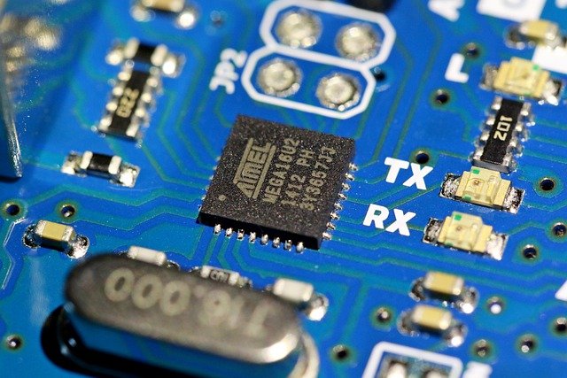 Close-up of a blue circuit board featuring a black microchip labeled "Atmel" with visible electronic components.