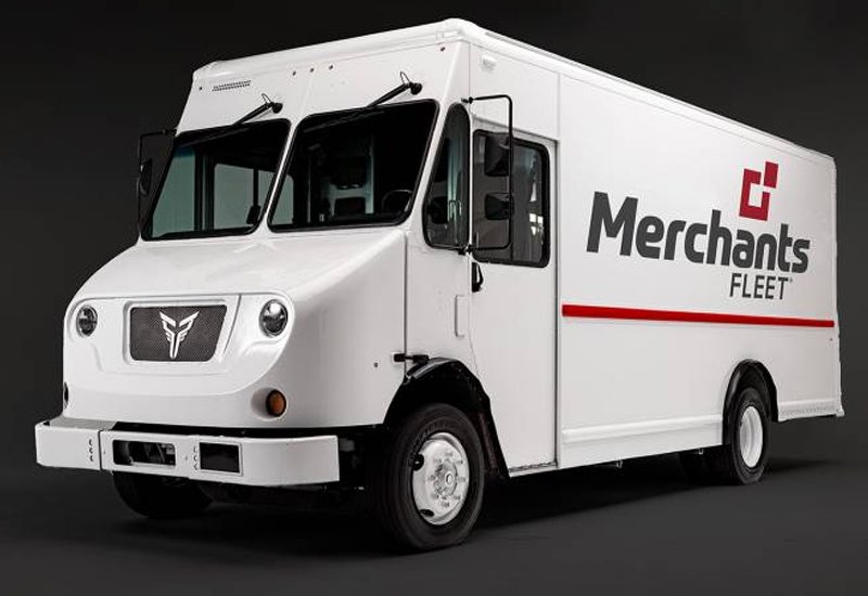 White delivery truck with "Merchants Fleet" logo on the side, parked against a dark background.