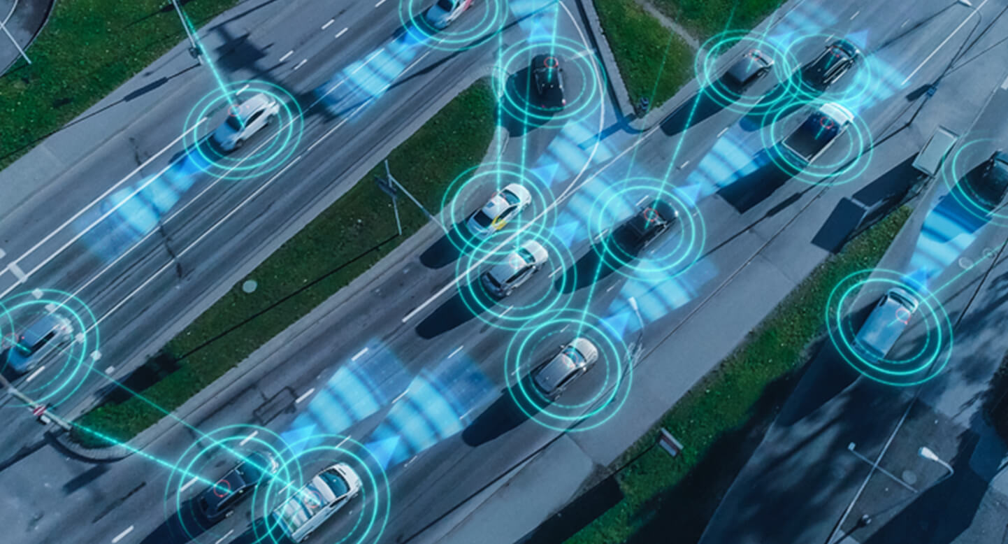 Aerial view of cars on a road with blue digital connectivity overlays, suggesting smart traffic technology.