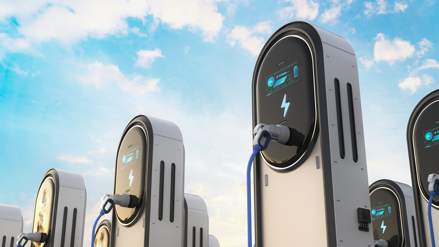 Multiple electric vehicle charging stations under a blue sky with clouds.
