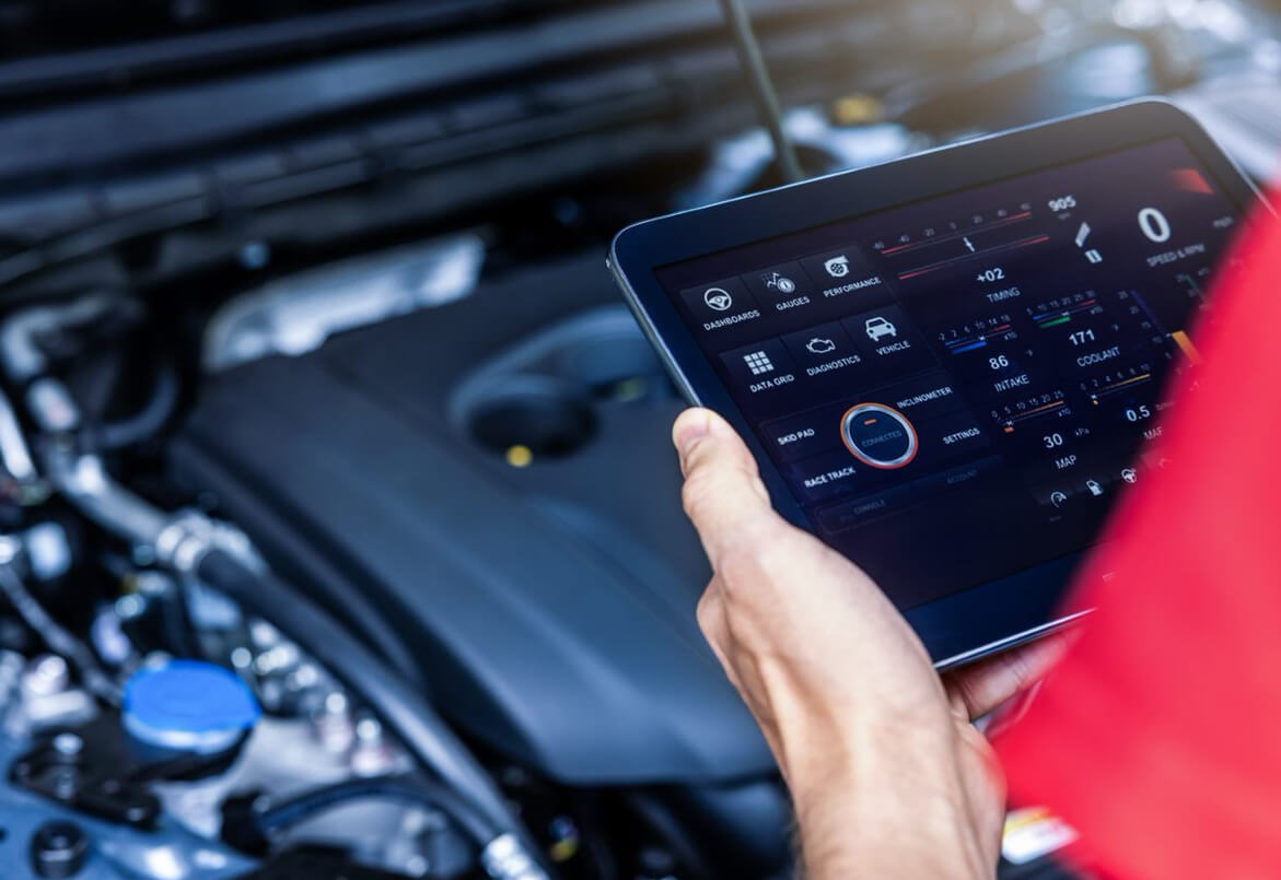 Person using a tablet to diagnose a car engine, with various stats displayed on the screen.