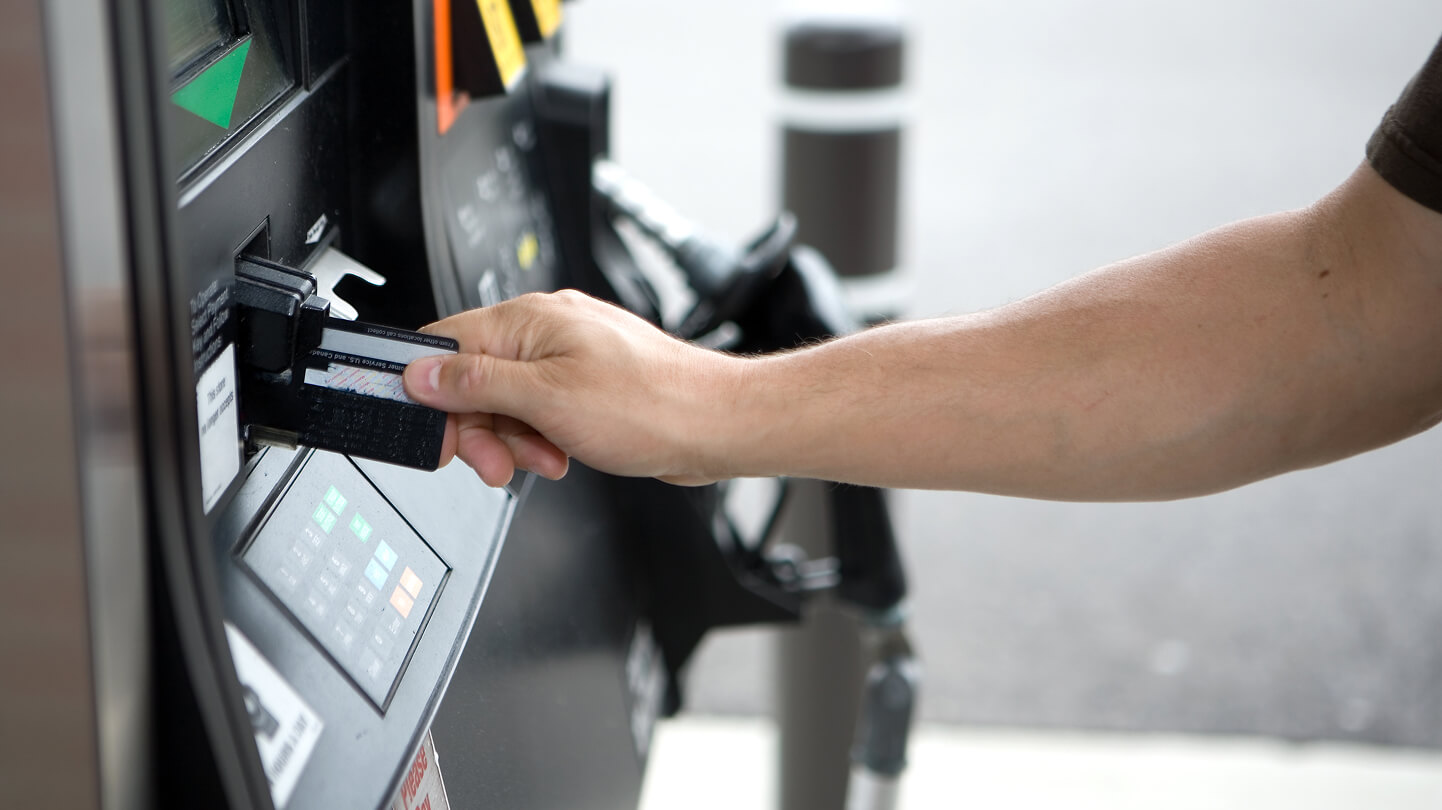 A person inserts a credit card into a gas station pump.
