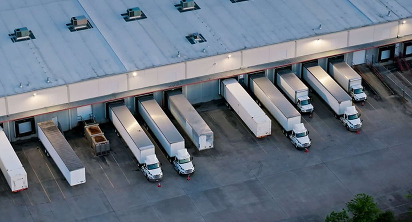 Aerial view of a warehouse loading dock with multiple trucks backed into bays.