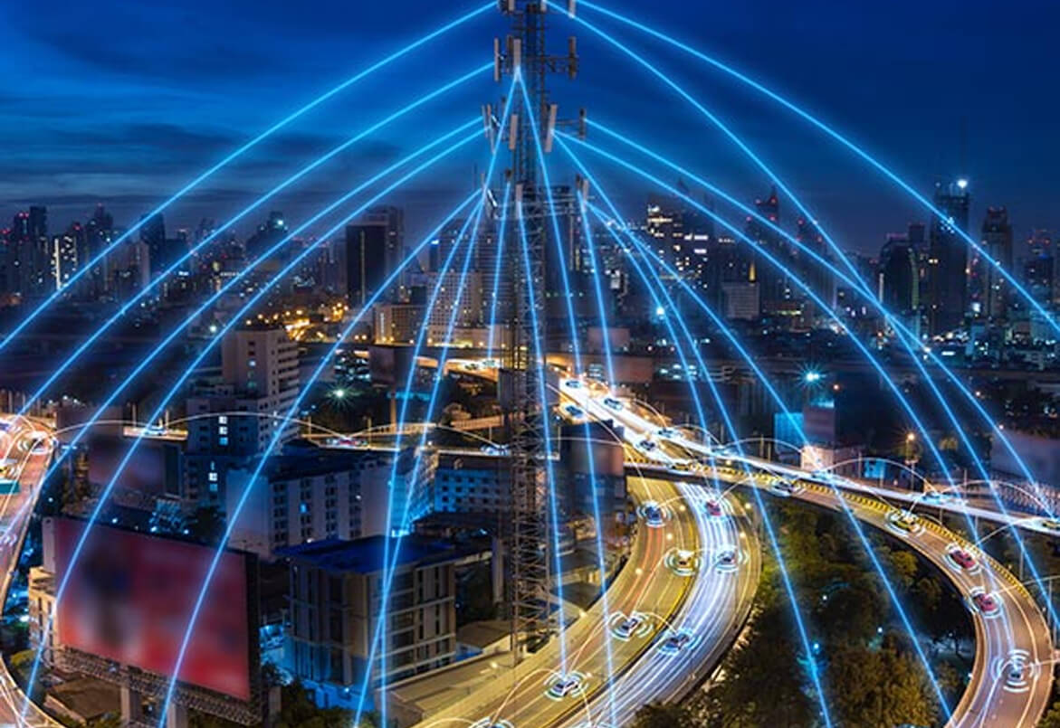 A cityscape at night with bright blue lines illustrating network connectivity over roads and buildings.
